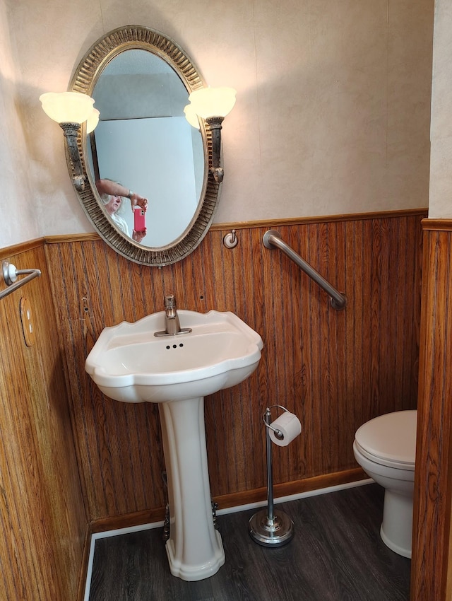 bathroom with wainscoting, wooden walls, toilet, and wood finished floors