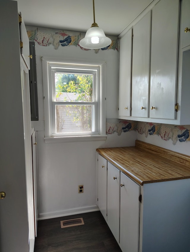 kitchen featuring visible vents, baseboards, dark wood-style floors, hanging light fixtures, and white cabinetry