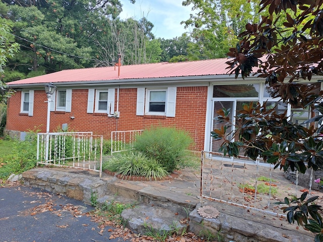 view of front of property with brick siding, metal roof, and driveway