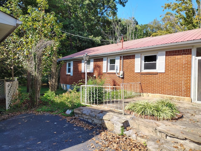 single story home featuring metal roof and brick siding