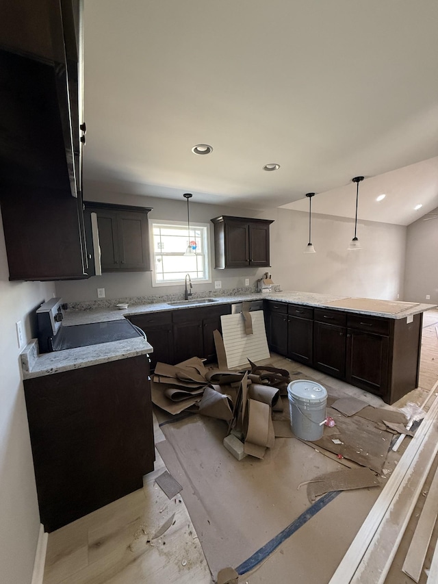 kitchen featuring recessed lighting, a peninsula, a sink, dark brown cabinets, and decorative light fixtures