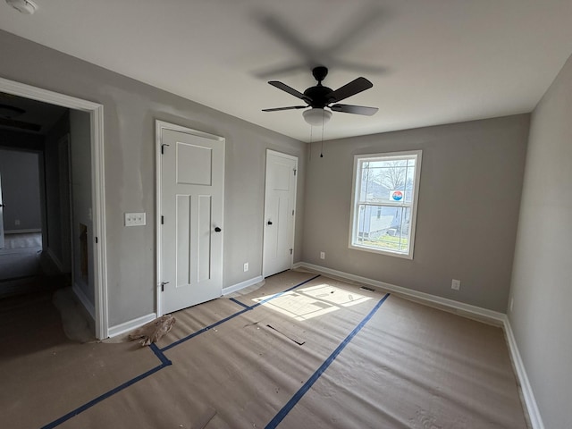 unfurnished bedroom featuring ceiling fan, visible vents, baseboards, and wood finished floors