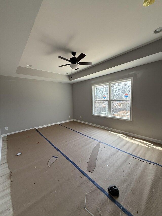 spare room featuring baseboards, a tray ceiling, and ceiling fan