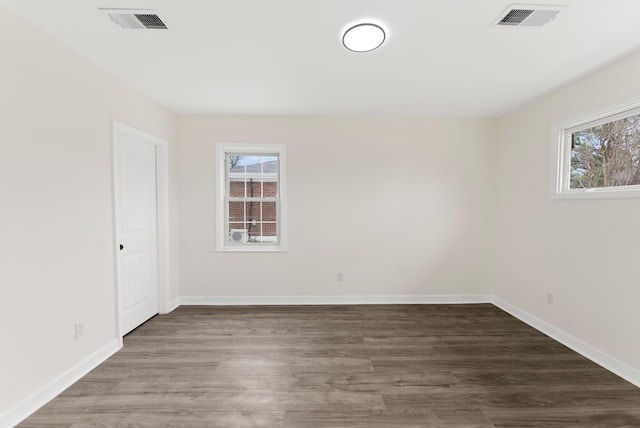 unfurnished room with a healthy amount of sunlight, visible vents, and wood finished floors