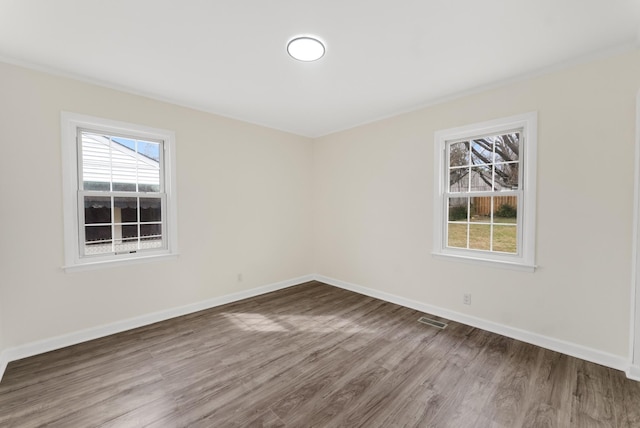 unfurnished room with visible vents, baseboards, and wood finished floors