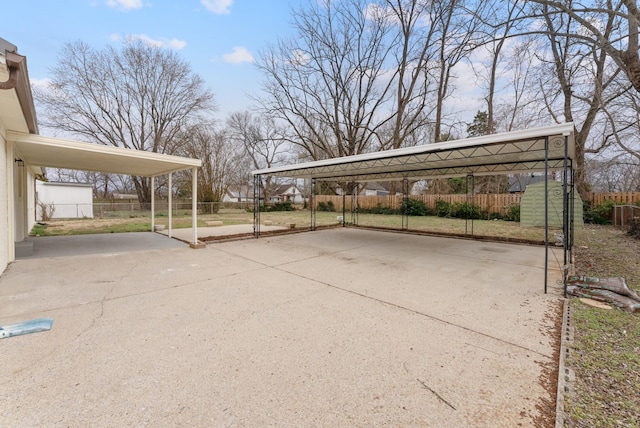 view of parking / parking lot with a carport, fence, and concrete driveway