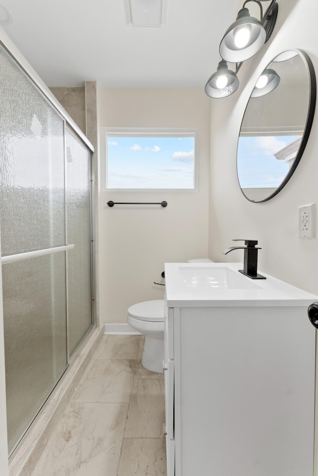 bathroom featuring toilet, marble finish floor, vanity, and a stall shower