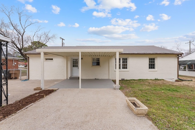 view of front of home with metal roof, an attached carport, brick siding, driveway, and a front yard