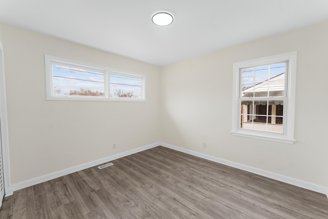 spare room featuring wood finished floors, visible vents, and baseboards