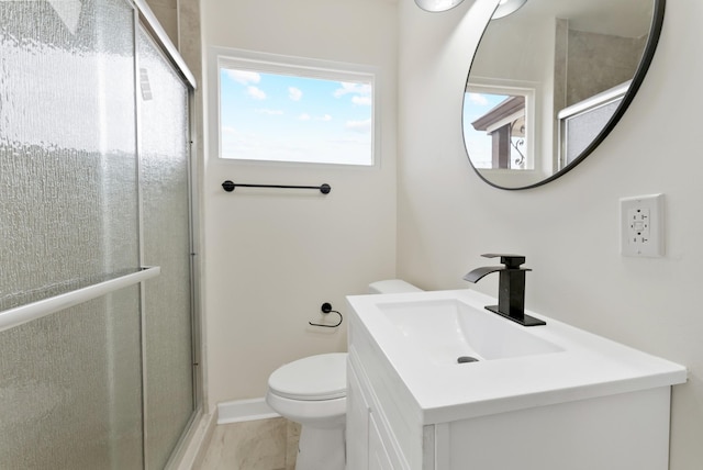 full bathroom featuring a stall shower, baseboards, vanity, and toilet