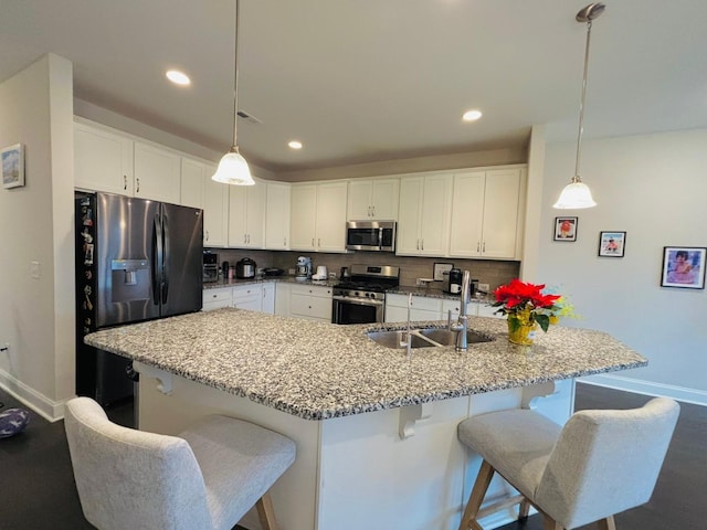 kitchen with tasteful backsplash, visible vents, a kitchen bar, appliances with stainless steel finishes, and a sink