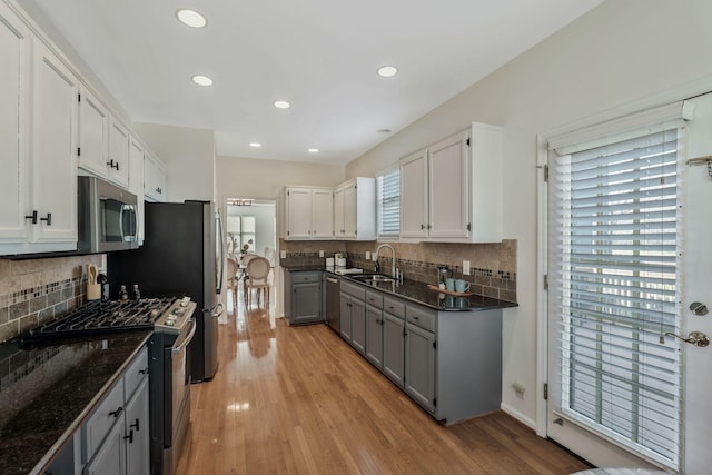 kitchen featuring stainless steel appliances, gray cabinets, light wood-style flooring, white cabinetry, and a sink