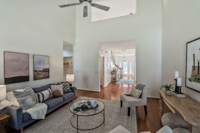 living room featuring stairs, ceiling fan, baseboards, and wood finished floors