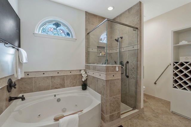 full bath with a stall shower, tile patterned flooring, and a jetted tub