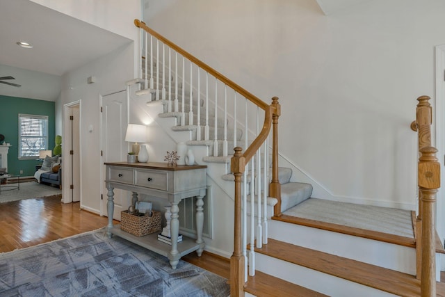 staircase with a towering ceiling, baseboards, and wood finished floors