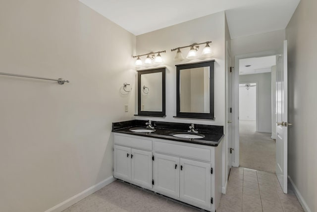 bathroom with double vanity, tile patterned flooring, a sink, and baseboards