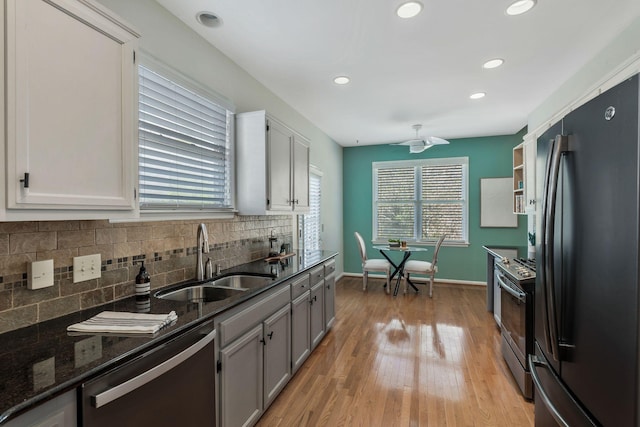 kitchen with tasteful backsplash, electric range oven, stainless steel dishwasher, freestanding refrigerator, and a sink