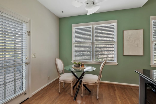 dining area with wood finished floors, a ceiling fan, and baseboards