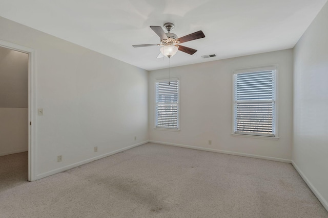 carpeted empty room featuring a ceiling fan, visible vents, plenty of natural light, and baseboards