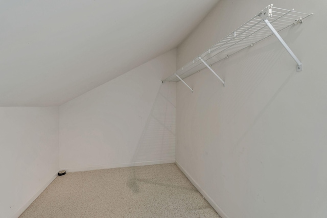 walk in closet featuring light carpet and vaulted ceiling