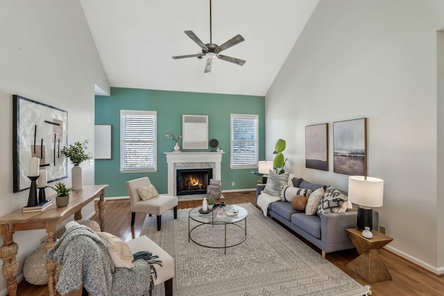 living area with plenty of natural light, a premium fireplace, high vaulted ceiling, and wood finished floors