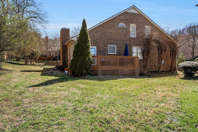 back of property with a chimney, brick siding, a yard, and a deck