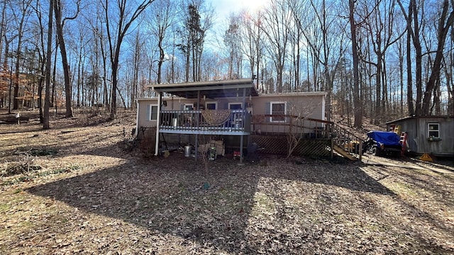 rear view of property featuring a storage shed, stairs, a deck, and an outbuilding