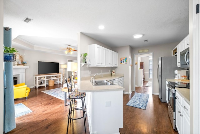 kitchen featuring visible vents, open floor plan, stainless steel appliances, a fireplace, and a sink