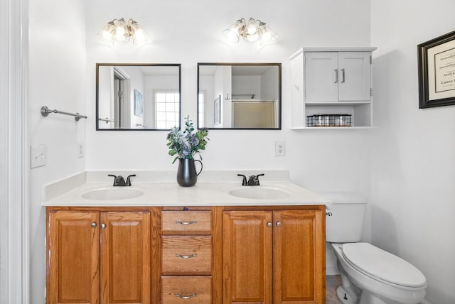 full bathroom with double vanity, a sink, and toilet