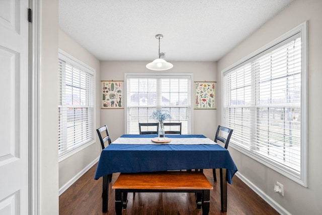 dining area with a textured ceiling, baseboards, and wood finished floors