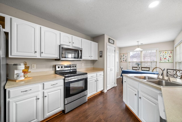 kitchen with stainless steel appliances, dark wood-style flooring, a sink, white cabinetry, and light countertops