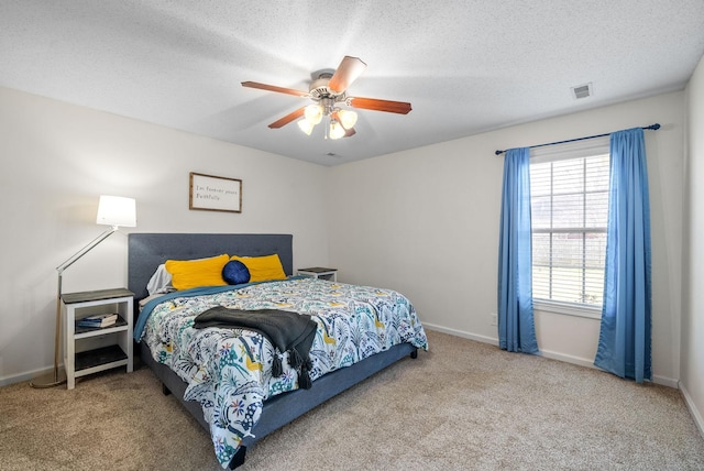 carpeted bedroom with visible vents, ceiling fan, a textured ceiling, and baseboards