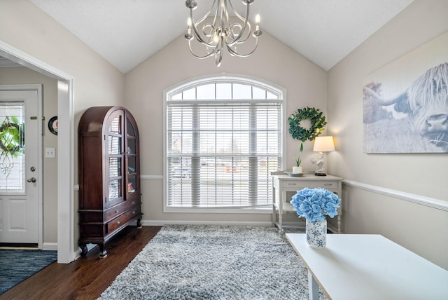 entrance foyer featuring baseboards, vaulted ceiling, dark wood-style flooring, and a chandelier