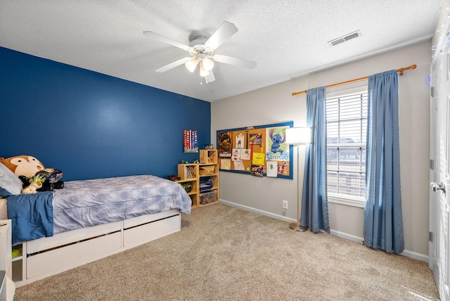 carpeted bedroom with a ceiling fan, baseboards, visible vents, and a textured ceiling