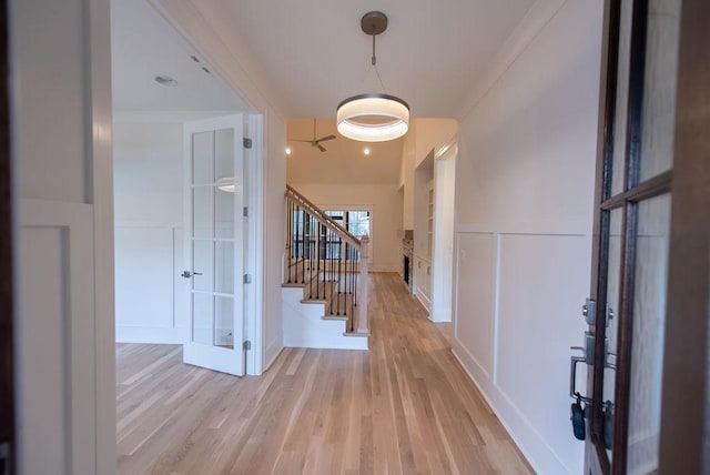 foyer with a decorative wall, stairway, and light wood-style floors