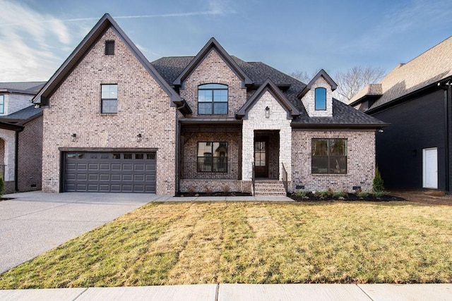 french country inspired facade featuring a shingled roof, concrete driveway, an attached garage, a front lawn, and brick siding