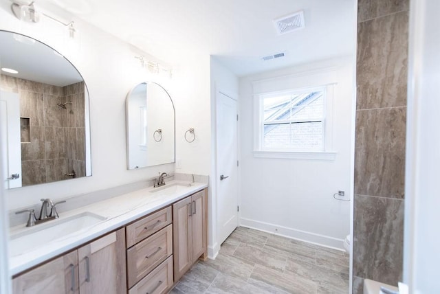 full bathroom with double vanity, a sink, visible vents, and baseboards