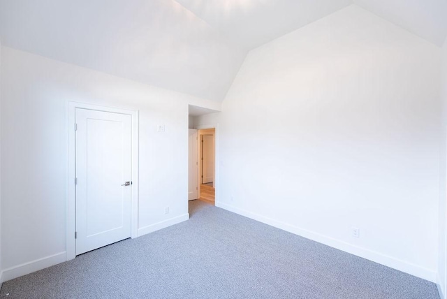 unfurnished bedroom with lofted ceiling, carpet, and baseboards