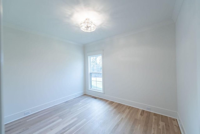 spare room featuring ornamental molding, baseboards, and light wood finished floors