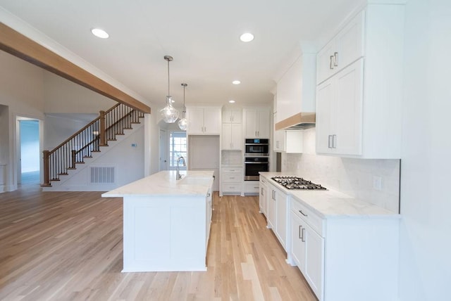 kitchen with visible vents, light wood-style floors, white cabinetry, backsplash, and light stone countertops