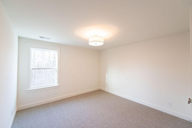spare room with baseboards, visible vents, and light colored carpet