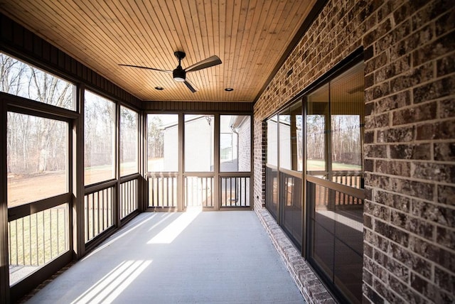 unfurnished sunroom featuring wood ceiling and a ceiling fan