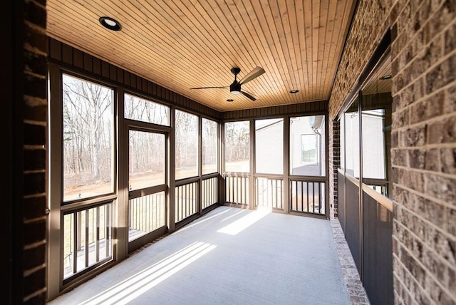 unfurnished sunroom featuring a healthy amount of sunlight, wooden ceiling, and a ceiling fan