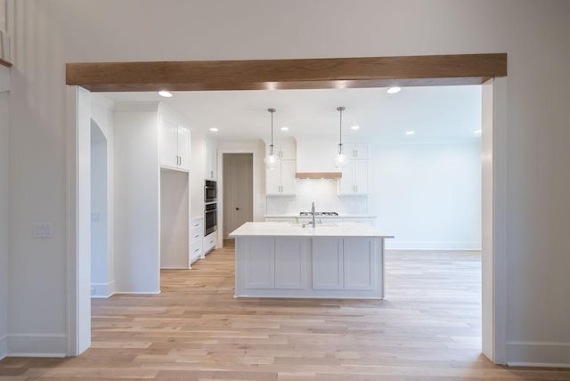 kitchen with baseboards, white cabinets, decorative backsplash, light countertops, and light wood-style floors