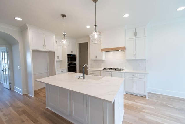 kitchen with white cabinets, arched walkways, backsplash, and a sink