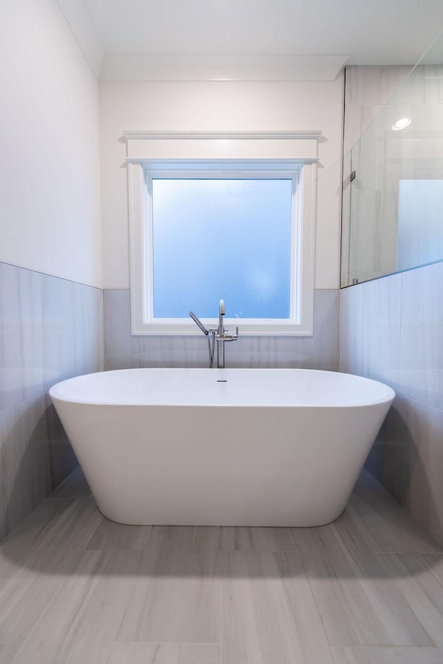 full bathroom with a freestanding tub, a wainscoted wall, tile walls, and a walk in shower