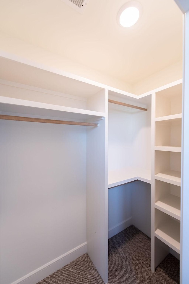 walk in closet featuring dark carpet