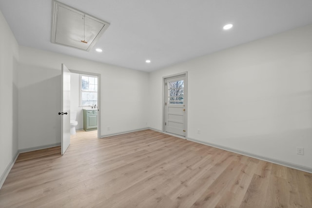 empty room with light wood-style flooring, plenty of natural light, and attic access