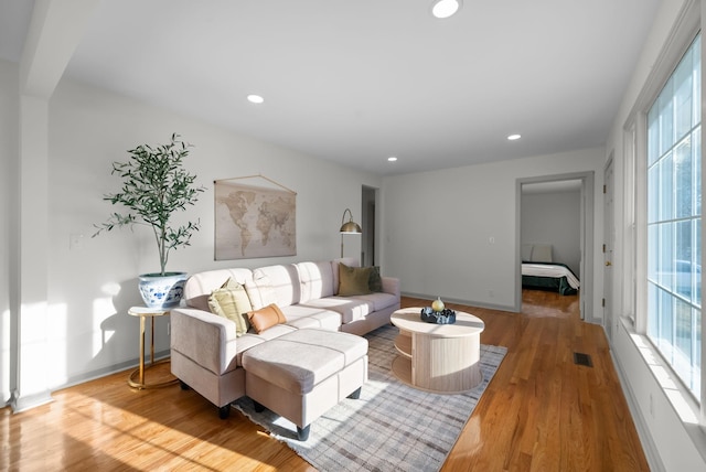 living area featuring baseboards, visible vents, wood finished floors, and recessed lighting