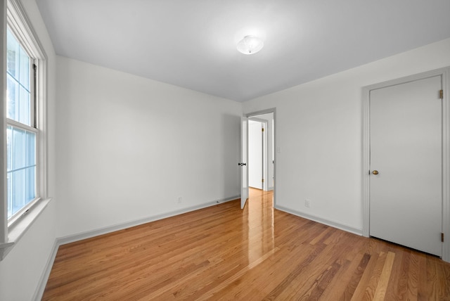 unfurnished bedroom with light wood-style floors, multiple windows, and baseboards